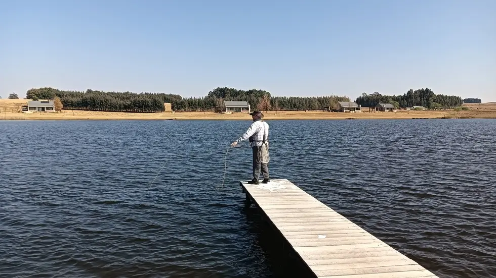 Beginner client with first trout, guided net support at the bank